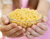 Little girl holding bowl with pasta